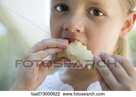 Stock Image - Little girl eatiing apple. Fotosearch