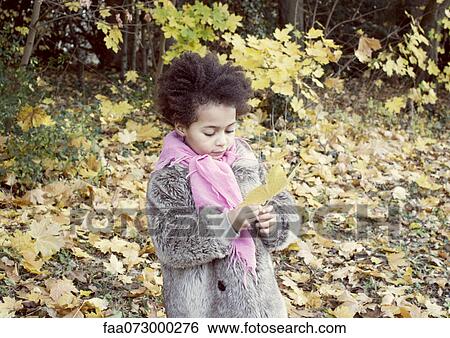 Stock Photograph - Little girl holding autumn leaf, portrait. Fotosearch