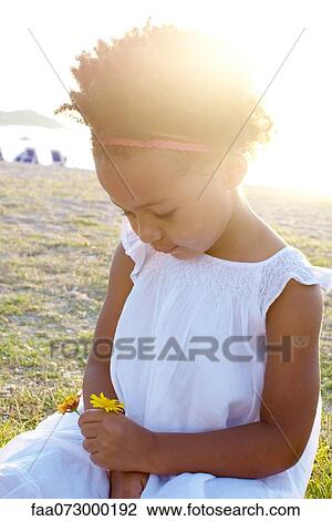 Stock Image - Little girl holding flowers, portrait. Fotosearch