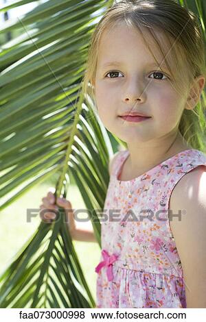 Stock Photo - Little girl holding palm leaf, portrait. Fotosearch