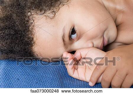Stock Photo - Little girl lying down, cropped portrait. Fotosearch