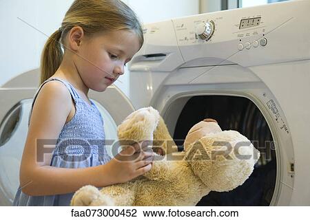 Stock Image - Little girl playing with teddy bear. Fotosearch