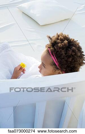Little girl relaxing with flower in hand View Large Photo Image Picture - Little girl relaxing with flower in hand. Fotosearch