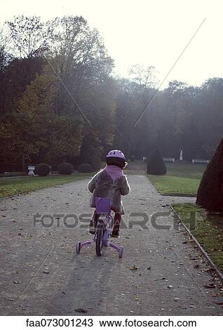 Stock Image - Little girl riding bicycle, rear view. Fotosearch