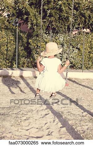 Stock Photography - Little girl sitting on swing, rear view. Fotosearch