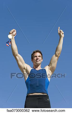 Male athlete holding up gold medal View Large Photo Image Stock Image - Male athlete holding up gold medal. Fotosearch