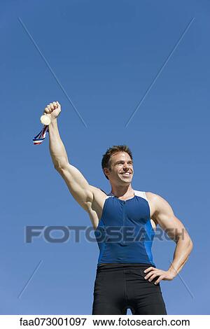 Male athlete holding up gold medal View Large Photo Image Stock Photo - Male athlete holding up gold medal. Fotosearch