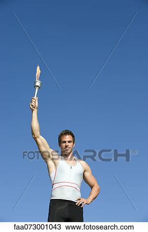 Stock Image - Male athlete holding up torch. Fotosearch