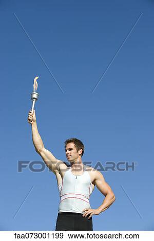 Stock Photo - Male athlete holding up torch. Fotosearch