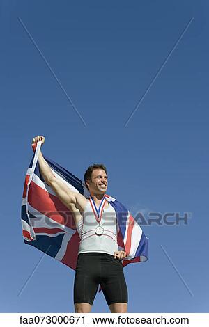 Male athlete on winner's podium, holding up British flag View Large Photo Image Stock Image - Male athlete on winner's podium, holding up British flag. Fotosearch