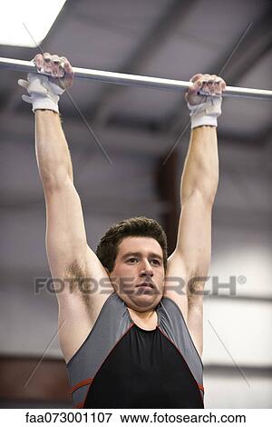 Male gymnast hanging from horizontal bar View Large Photo Image Stock Photo - Male gymnast hanging from horizontal bar. Fotosearch