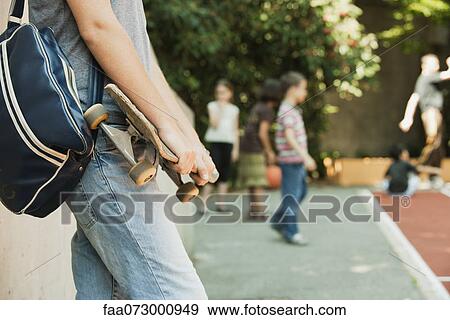 Man holding skateboard, mid section View Large Photo Image Stock Photo - Man holding skateboard, mid section. Fotosearch