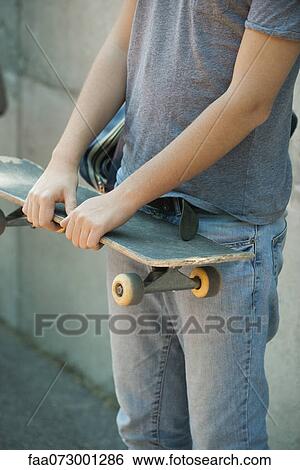 Man holding skateboard, mid section View Large Photo Image Stock Photograph - Man holding skateboard, mid section. Fotosearch