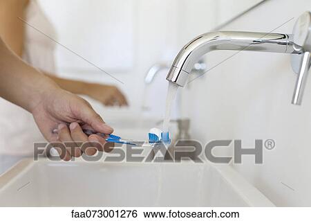 Man holding toothbrush under faucet, cropped View Large Photo Image Stock Photograph - Man holding toothbrush under faucet, cropped. Fotosearch