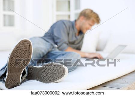 Man lying on bed using laptop computer View Large Photo Image Stock Image - Man lying on bed using laptop computer. Fotosearch