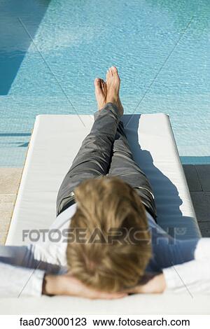 Man relaxing on lounge chair beside pool View Large Photo Image Stock Image - Man relaxing on lounge chair beside pool. Fotosearch