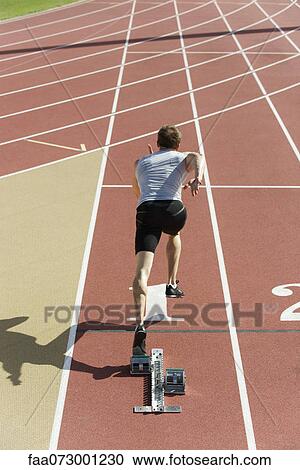 Stock Image - Man running on track, rear view. Fotosearch