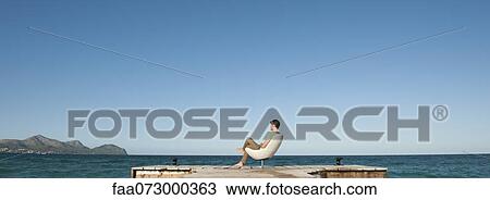 Man siting at end of dock looking at view, rear view View Large Photo Image Stock Image - Man siting at end of dock looking at view, rear view. Fotosearch