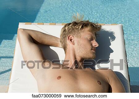 Stock Photo - Man sunbathing beside pool. Fotosearch