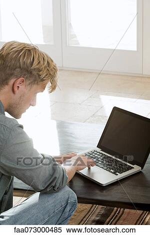 Stock Photography - Man using laptop computer at home. Fotosearch
