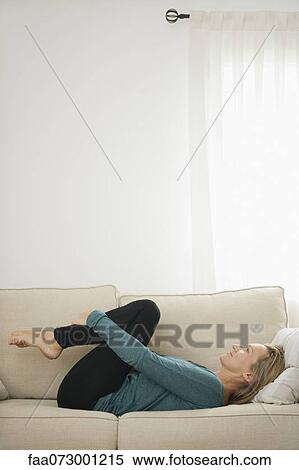 Mature woman lying on couch hugging knees View Large Photo Image Stock Photography - Mature woman lying on couch hugging knees. Fotosearch