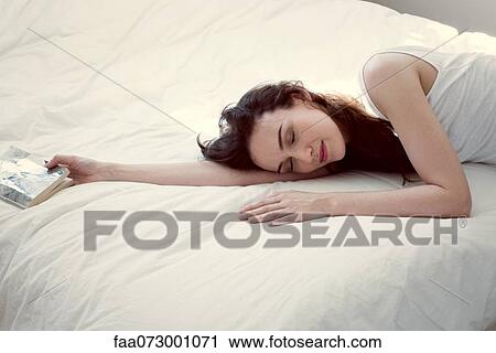 Stock Image - Mid-adult woman napping on bed. Fotosearch
