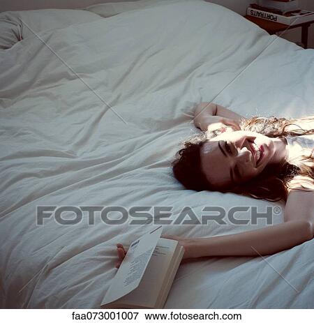 Stock Photo - Mid-adult woman relaxing on bed, cropped. Fotosearch
