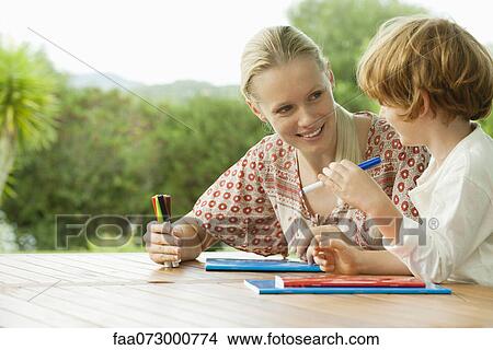 Mother and son sitting together with booklets and felt tip pens View Large Photo Image Picture - Mother and son sitting together with booklets and felt tip pens. Fotosearch