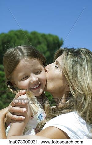 Mother kissing daughter's cheek View Large Photo Image Stock Image - Mother kissing daughter's cheek. Fotosearch