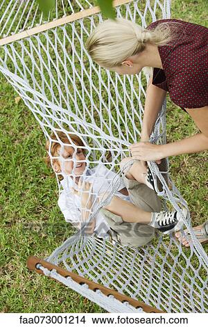 Picture - Mother playfully wrapping son in hammock. Fotosearch