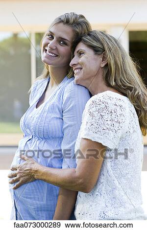 Mother putting hand on pregnant daughter's stomach View Large Photo Image Stock Photo - Mother putting hand on pregnant daughter's stomach. Fotosearch