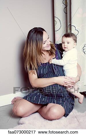 Stock Photo - Pregnant mother holding baby girl, portrait. Fotosearch