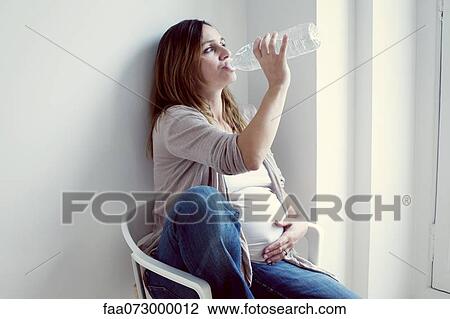 Pregnant woman drinking water from bottle View Large Photo Image Stock Image - Pregnant woman drinking water from bottle. Fotosearch
