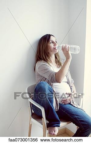 Stock Photograph - Pregnant woman drinking water from bottle. Fotosearch