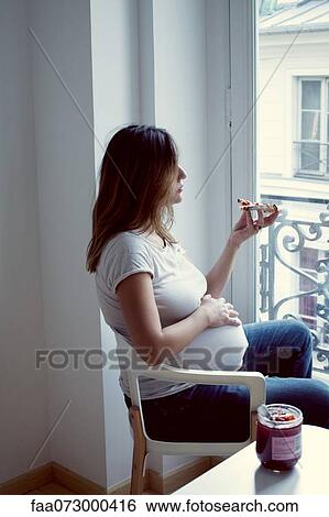Stock Photograph - Pregnant woman eating toast with jam. Fotosearch