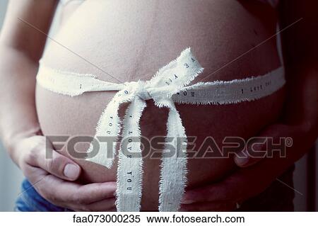 Pregnant woman with ribbon wrapping around stomach, mid section View Large Photo Image Stock Photography - Pregnant woman with ribbon wrapping around stomach, mid section. Fotosearch