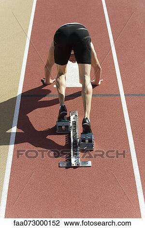 Runner crouched at startling line, rear view View Large Photo Image Stock Image - Runner crouched at startling line, rear view. Fotosearch