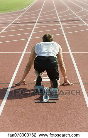 Runner crouched at startling line, rear view View Large Photo Image Stock Image - Runner crouched at startling line, rear view. Fotosearch
