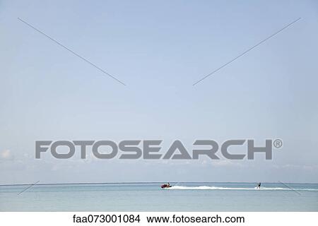 Seascape, person water skiing in the distance View Large Photo Image Picture - Seascape, person water skiing in the distance. Fotosearch