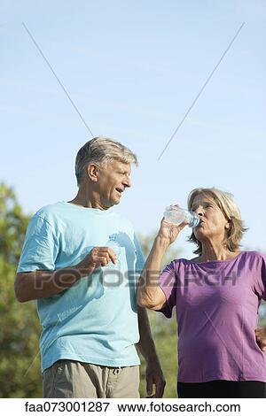 Senior couple drinking bottled water outdoors View Large Photo Image Stock Photo - Senior couple drinking bottled water outdoors. Fotosearch