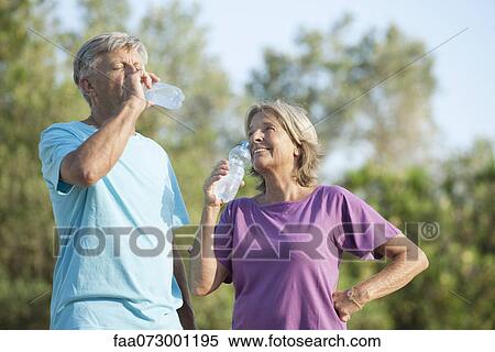 Stock Photography - Senior couple drinking bottled water outdoors. Fotosearch