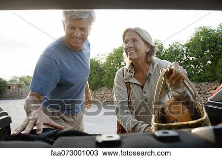 Stock Image - Senior couple loading bags into car. Fotosearch