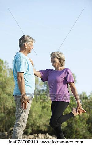 Senior couple outdoors, woman holding on to man for support while stretching View Large Photo Image Stock Photo - Senior couple outdoors, woman holding on to man for support while stretching. Fotosearch