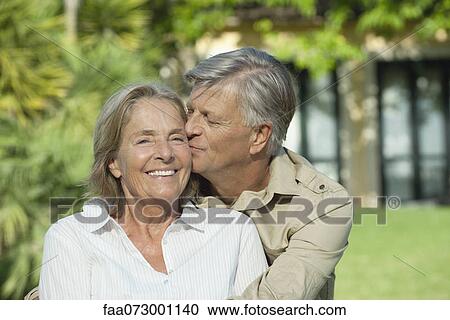 Stock Image - Senior man kissing his wife on the cheek. Fotosearch