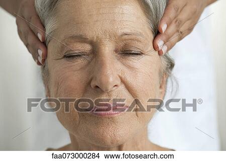 Senior woman having her temples massaged, cropped View Large Photo Image Picture - Senior woman having her temples massaged, cropped. Fotosearch