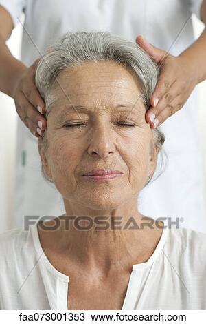 Stock Image - Senior woman having her temples massaged, cropped. Fotosearch