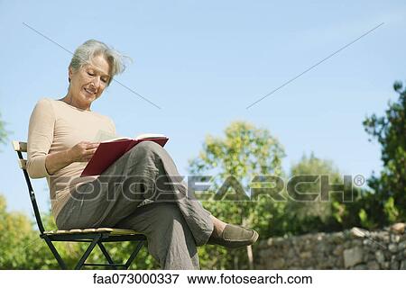 Senior woman reading book outdoors View Large Photo Image Stock Photo - Senior woman reading book outdoors. Fotosearch