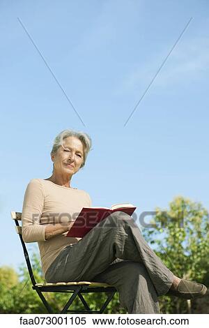 Senior woman sitting outdoors with book, portrait View Large Photo Image Stock Photography - Senior woman sitting outdoors with book, portrait. Fotosearch
