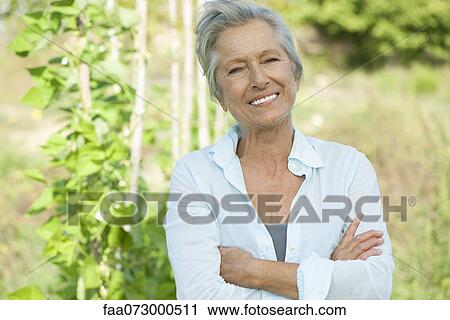 Stock Image - Senior woman with arms folded, portrait. Fotosearch