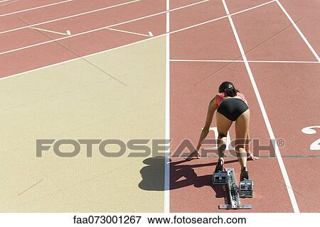 Woman crouched in starting position on running track, rear view View Large Photo Image Stock Photo - Woman crouched in starting position on running track, rear view. Fotosearch